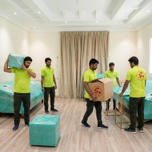 عمال نقل عفش بالرياض يحملون صناديق الأثاث داخل شقة